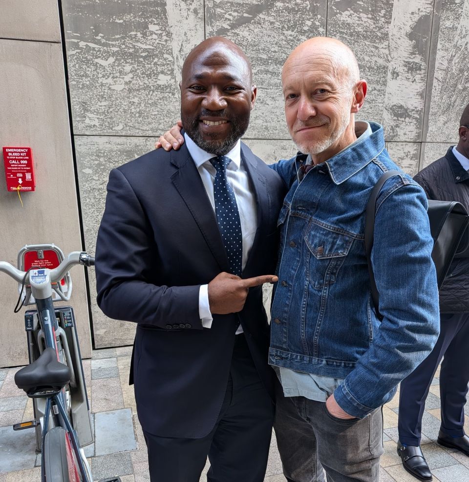 A man in a suit pointing at a man in a denim jacket